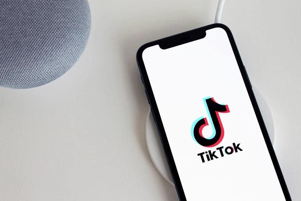Телефон с логотипом ТикТок лежит на белом столе
