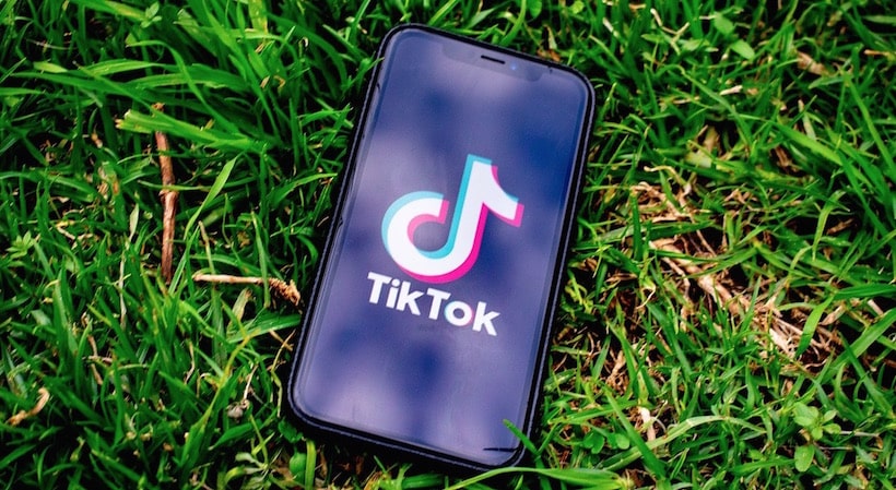 Телефон с логотипом ТикТок лежит на траве