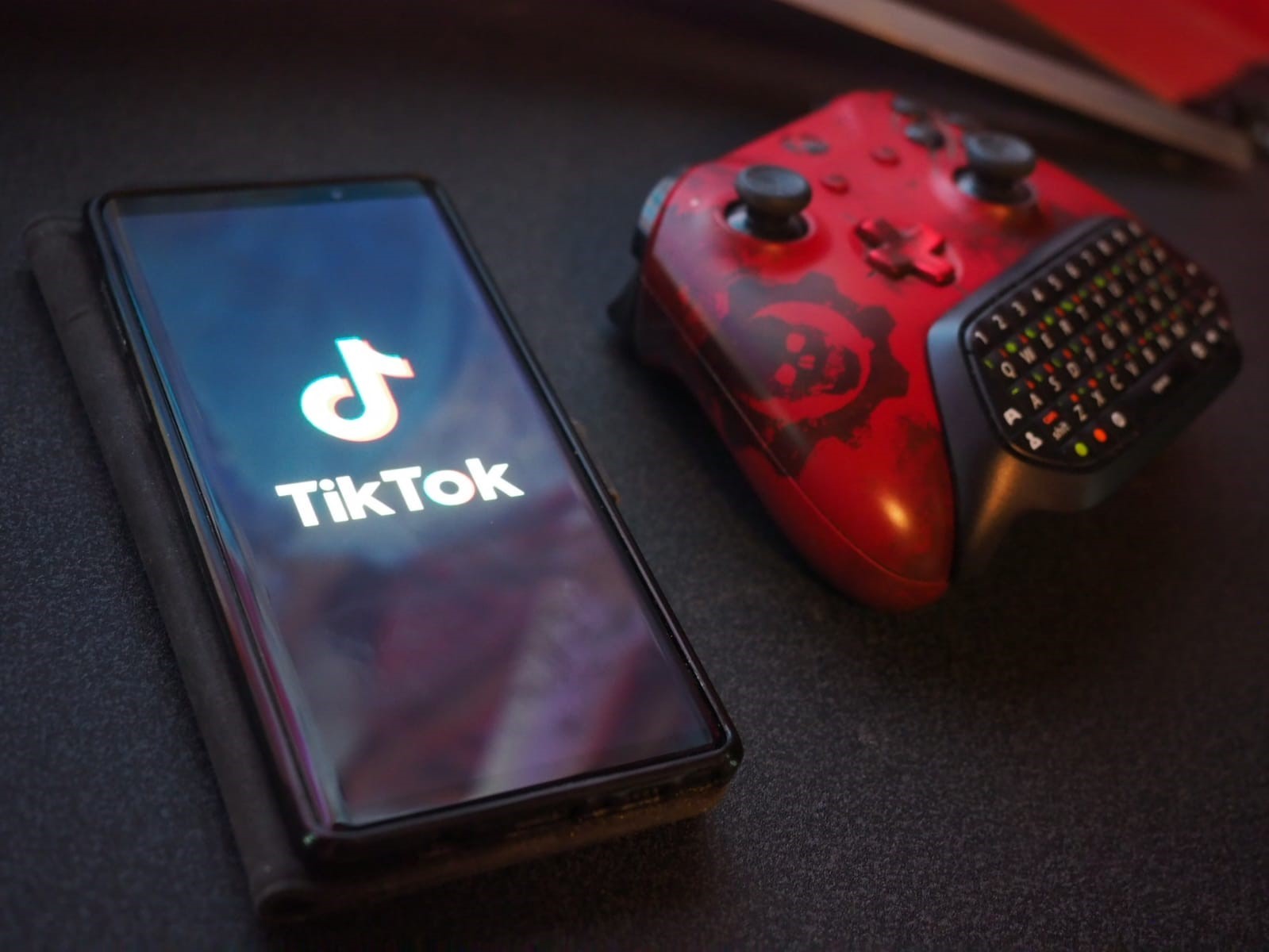 Телефон с логотипом ТикТок лежит рядом с приставкой
