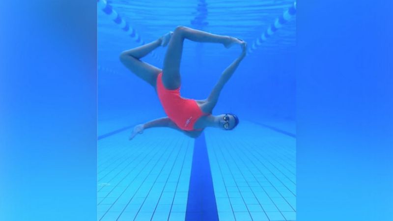 Девушка танцует под водой в бассейне